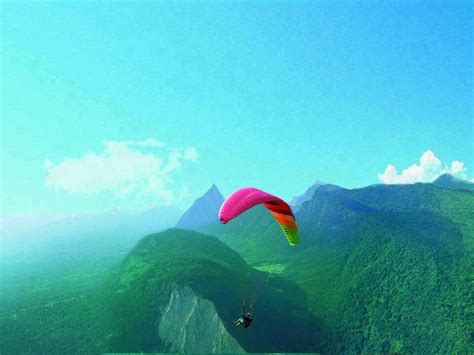 a person para sailing in the ocean with mountains in the backgrouds and ...