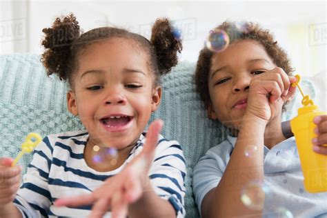 Black children blowing bubbles together - Stock Photo - Dissolve