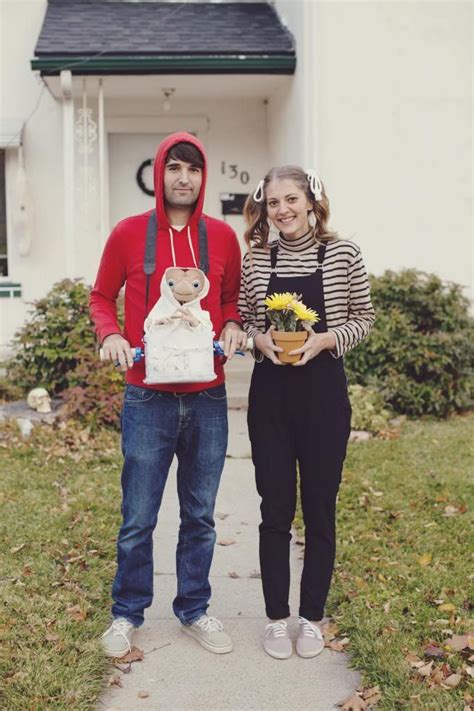 a man and woman standing in front of a white house with a teddy bear on ...