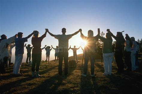 Circle of people holding hands. With arms up at Earth Day Ceremony as ...