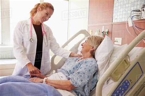 Female doctor talks to senior female patient in hospital bed - Stock ...