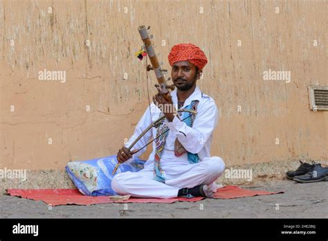 A local man in traditional dress plays a ravanahatha at Amber Fort (or ...