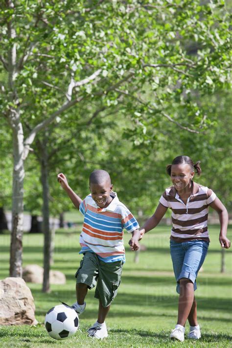 African American children playing soccer in park - Stock Photo - Dissolve