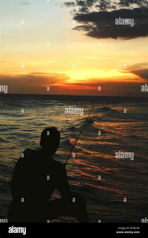 Silhouette Man Fishing In Sea At Sunset Stock Photo - Alamy