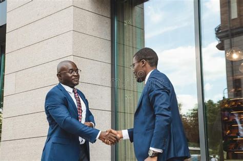 Two black african american businessmen in suits and glasses shake hands ...