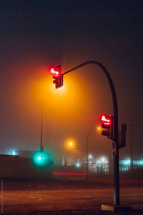 two traffic lights on a foggy street at night