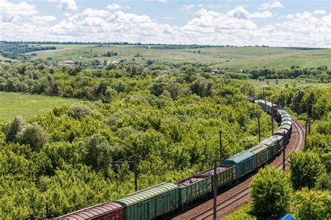 The Freight Railroad Train Rides through Fields and Hills Amidst Green ...