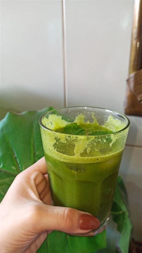 a person holding a green drink in their hand