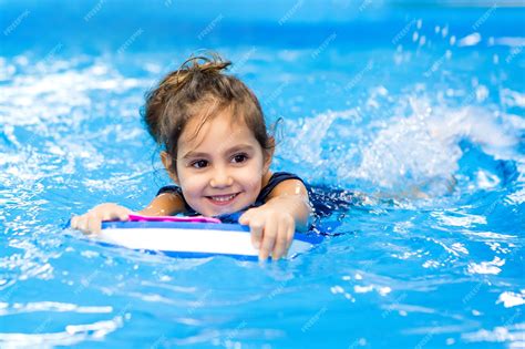 Premium Photo | Little girl learning to swim in the pool