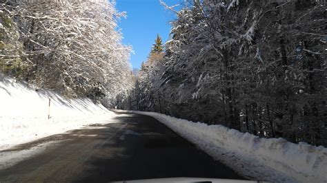 car driving on a snowy road surrounded by the forest under the snow ...