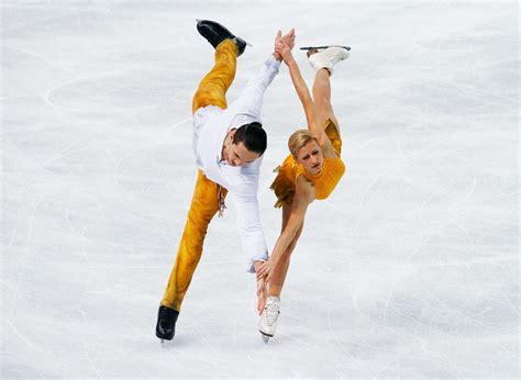 two people in yellow and white outfits doing tricks on an ice rink with ...