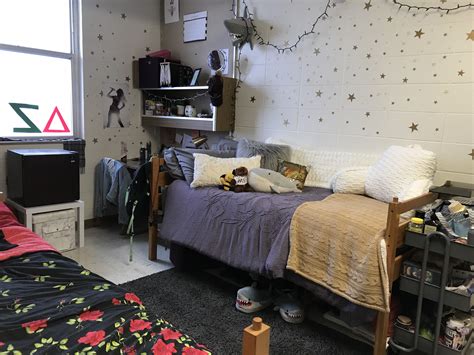 a dorm room with a bed, desk and shelves on the wall next to it