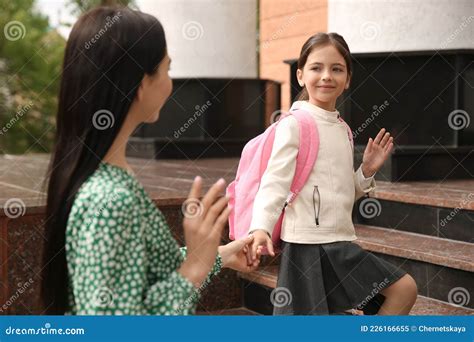 Little Girl Waving Goodbye To Mother Near School Entrance Outdoors ...