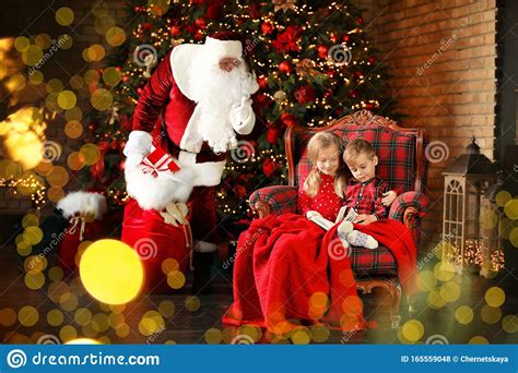 Santa Claus Sneaking in with Gifts while Children Reading Book Near ...