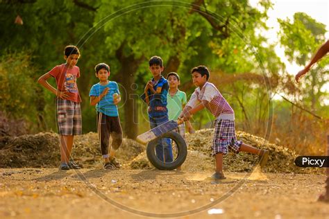 Image of Indian Rural Village Kids Playing Cricket In Fields-TA606336-Picxy