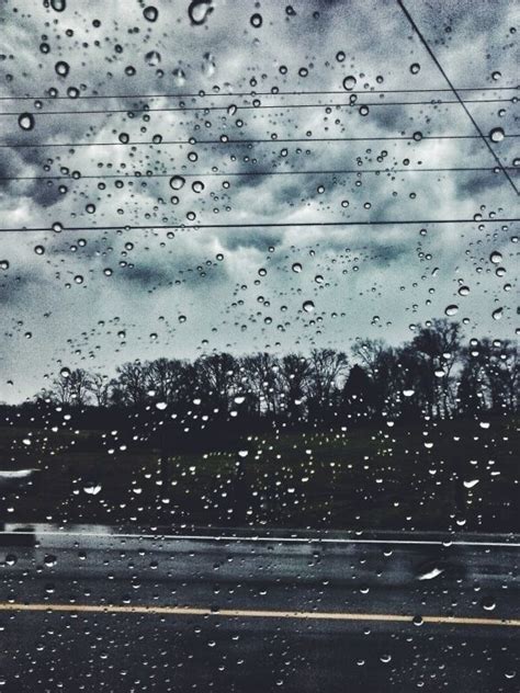 rain drops on the windshield of a car as it drives down a road with ...