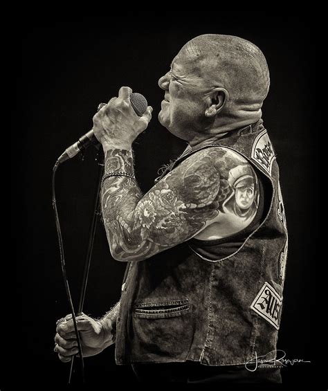 a man with tattoos on his arms and shoulder holding a microphone in ...