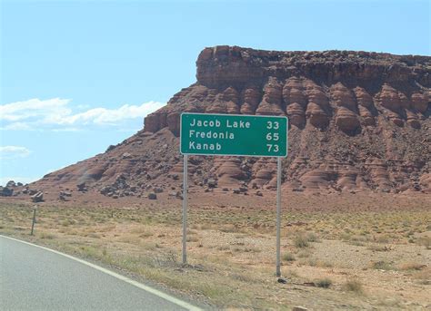 a highway sign on the side of a road in front of a large rock formation