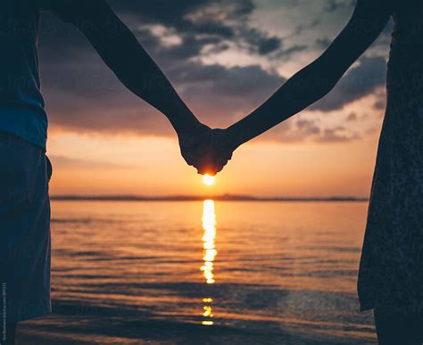 Couple Holding Hands On Nature Beach On Sunset by Ilya - Couple