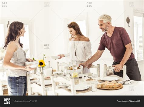 Family and friends setting the table for lunch stock photo - OFFSET