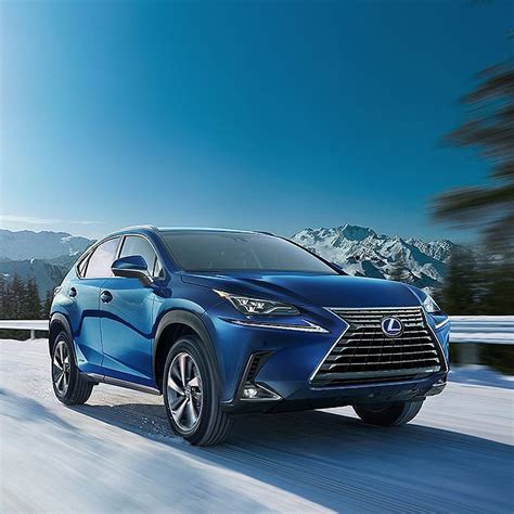 a blue car driving down a snowy road with mountains in the background