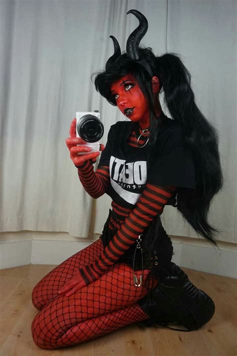 a woman with long black hair and red makeup is sitting on the floor ...