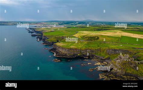 An aerial view of the historic Dunluce Castle and the green fields ...