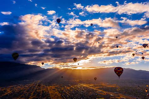 Hot air balloons flying at sunrise (with the Sandia Mountains in the ...