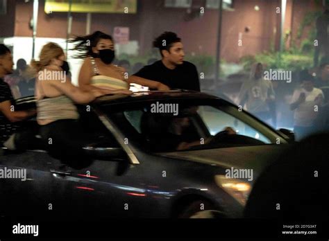 Los Angeles, California, USA. 18th Oct, 2020. People sit atop a car ...