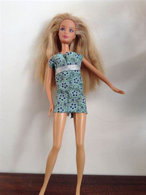 a doll with long blonde hair standing on a wooden floor