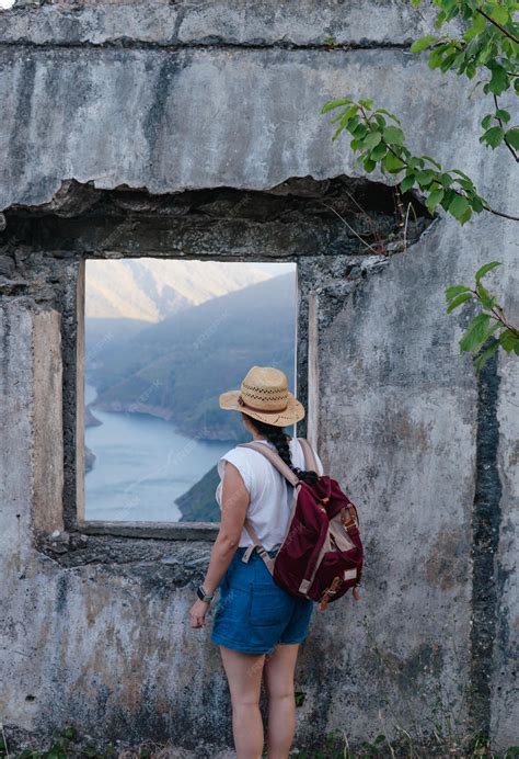 Premium Photo | Young girl with backpack and hat looks out of ruined ...