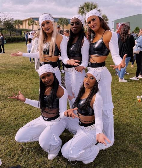 four women dressed in white pose for a photo together on the grass at ...