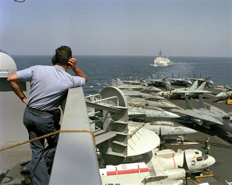 A crew member watches from the island as the miscellaneous flagship USS ...