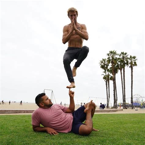 a man is doing tricks on another man's back in the grass near palm trees