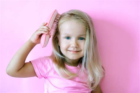 Premium Photo | Happy little girl combing her hair. Beauty and ...