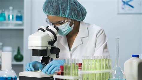 Woman scientist looking into microscope, biochemical research ...