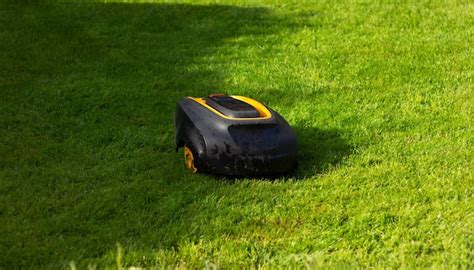 Premium Photo | Robot lawnmower mows grass on a green lawn automatic ...