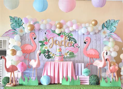 a birthday party with flamingos and balloons on the wall, table cloths ...