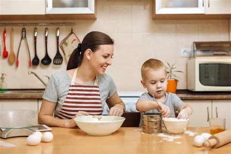 Little kid boy helps mother to cook Christmas ginger biscuit in light ...