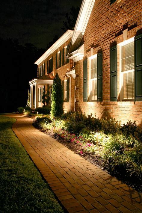 a house that is lit up at night with the lights on and flowers in the ...