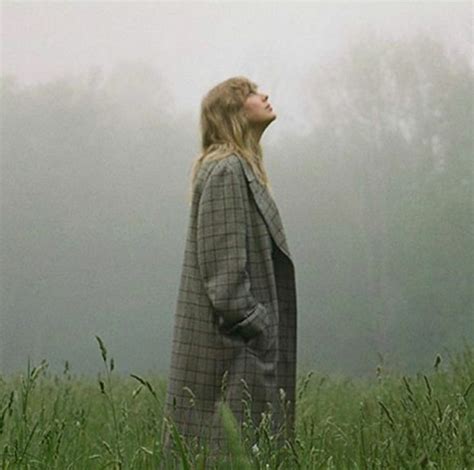 a woman standing in the middle of a field with her head turned to the side