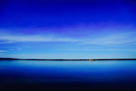 a deep blue lake and clear sky separated by a dark green shoreline on ...