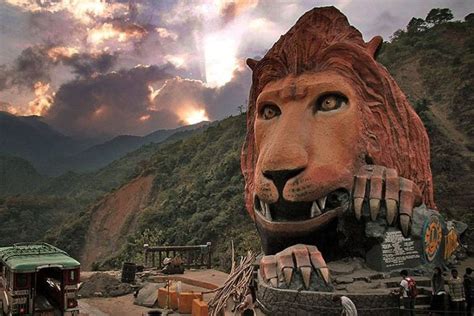 a giant lion statue in the middle of a mountainous area with people ...