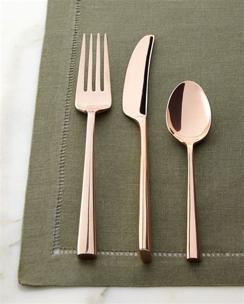 three forks, two spoons and one knife on a green place mat with ...