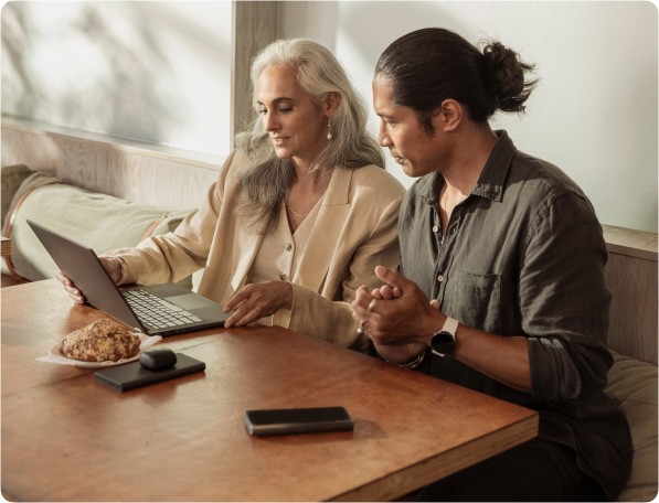 Man with smartphone looking at a woman’s computer