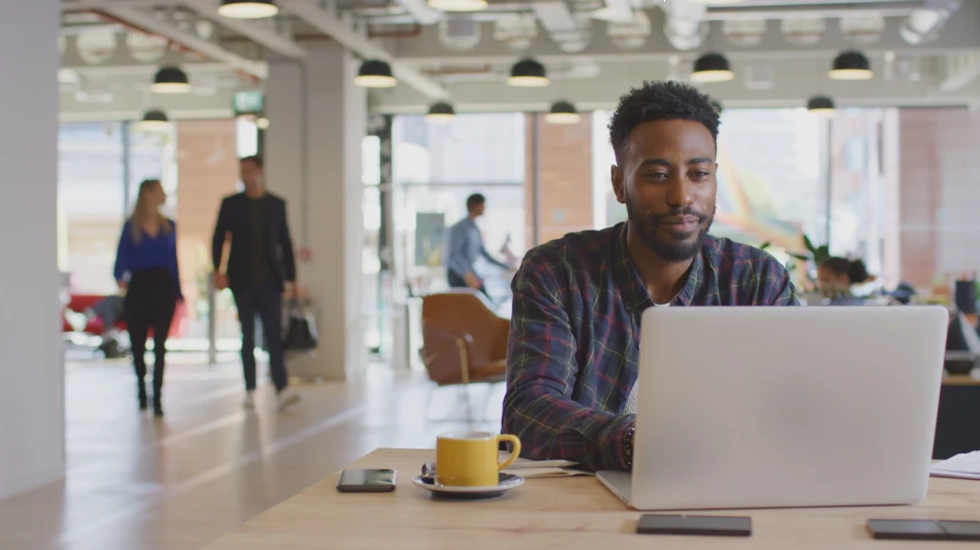 A young afro-american man working on his laptop in an office.