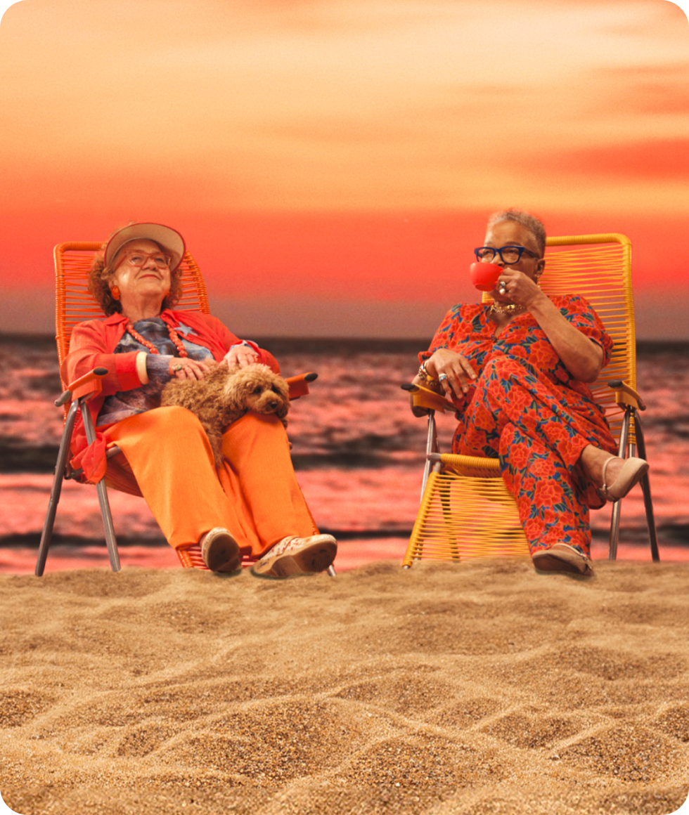 Two ladies sat on deck chairs on the beach, enjoying some sun