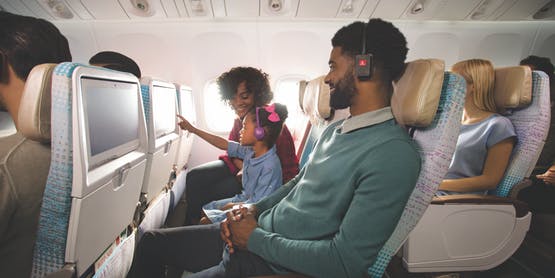 family of three sitting in Emirates Boeing 777 Economy Class choosing inflight entertainment