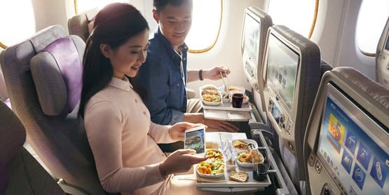 two passengers taking a picture of Economy Class meal onboard