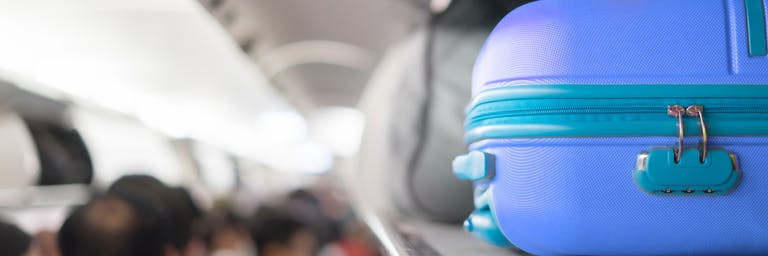 blue carry-on bag being stored in the overhead locker